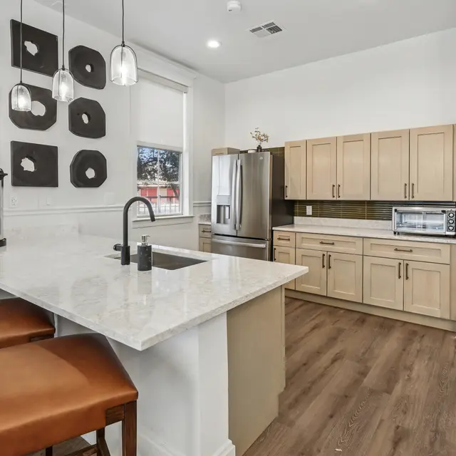 A kitchen with a white countertop and brown stools.